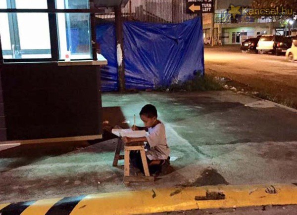 Az étterem kiszűrődő fényénél írja leckéjét a hajléktalan kisfiú